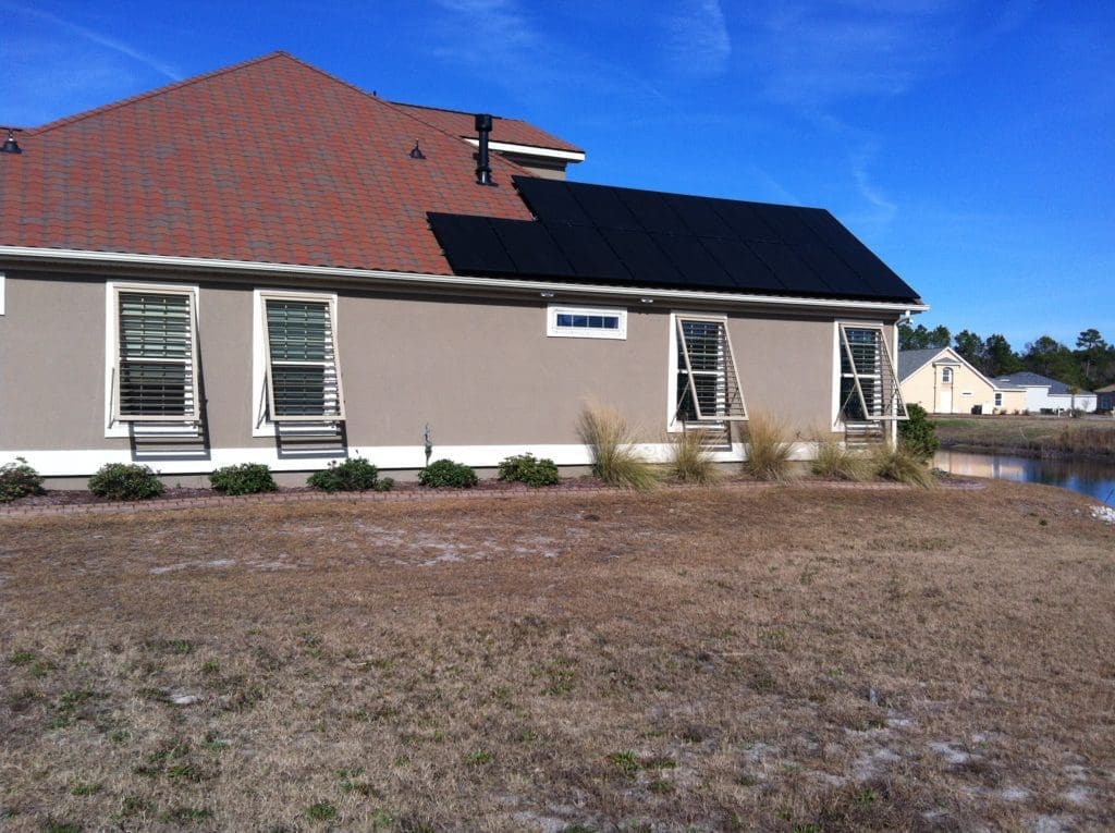 - american hurricane shutters House exterior featuring Bahama shutters and solar panels, showcasing energy-efficient design and protection from harsh weather conditions.