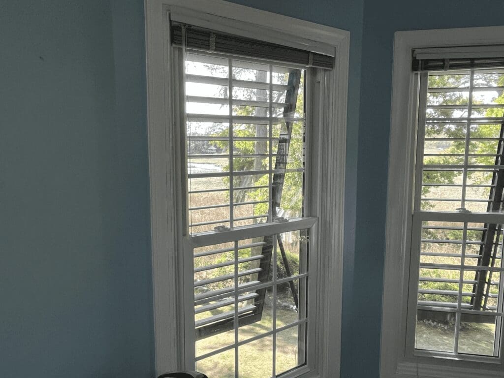 - american hurricane shutters Two windows with white hurricane shutters