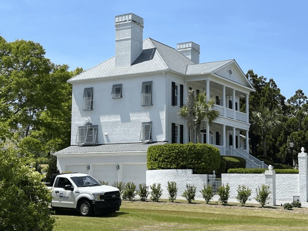White Southern Colonial home with black hurricane shutters, F-150.