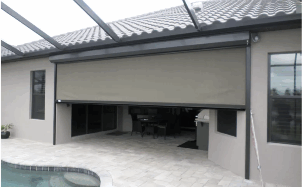 Screenshot 2025-10-25 at 104934 AM Rolldown storm shutter installed on a modern home, providing security and protection against hurricanes, with a view of an outdoor patio area.